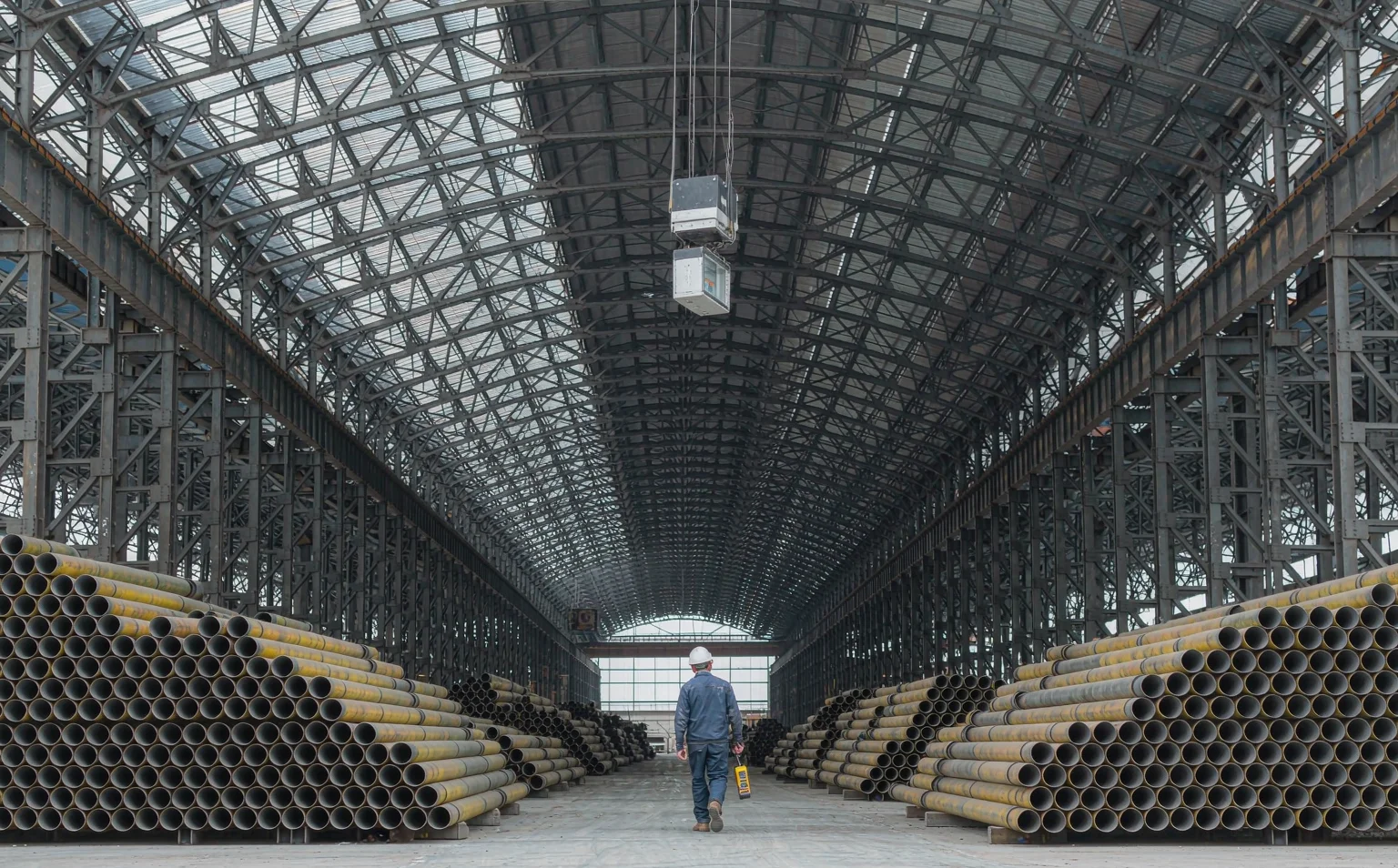 Steel-framed crane bay showing the receiver antenna mounted above the girder line and the reflected radio paths from roof trusses behind an operator walking the runway
