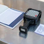 Compliance folder with a declaration of conformity and an industrial radio remote control transmitter on a steel desk
